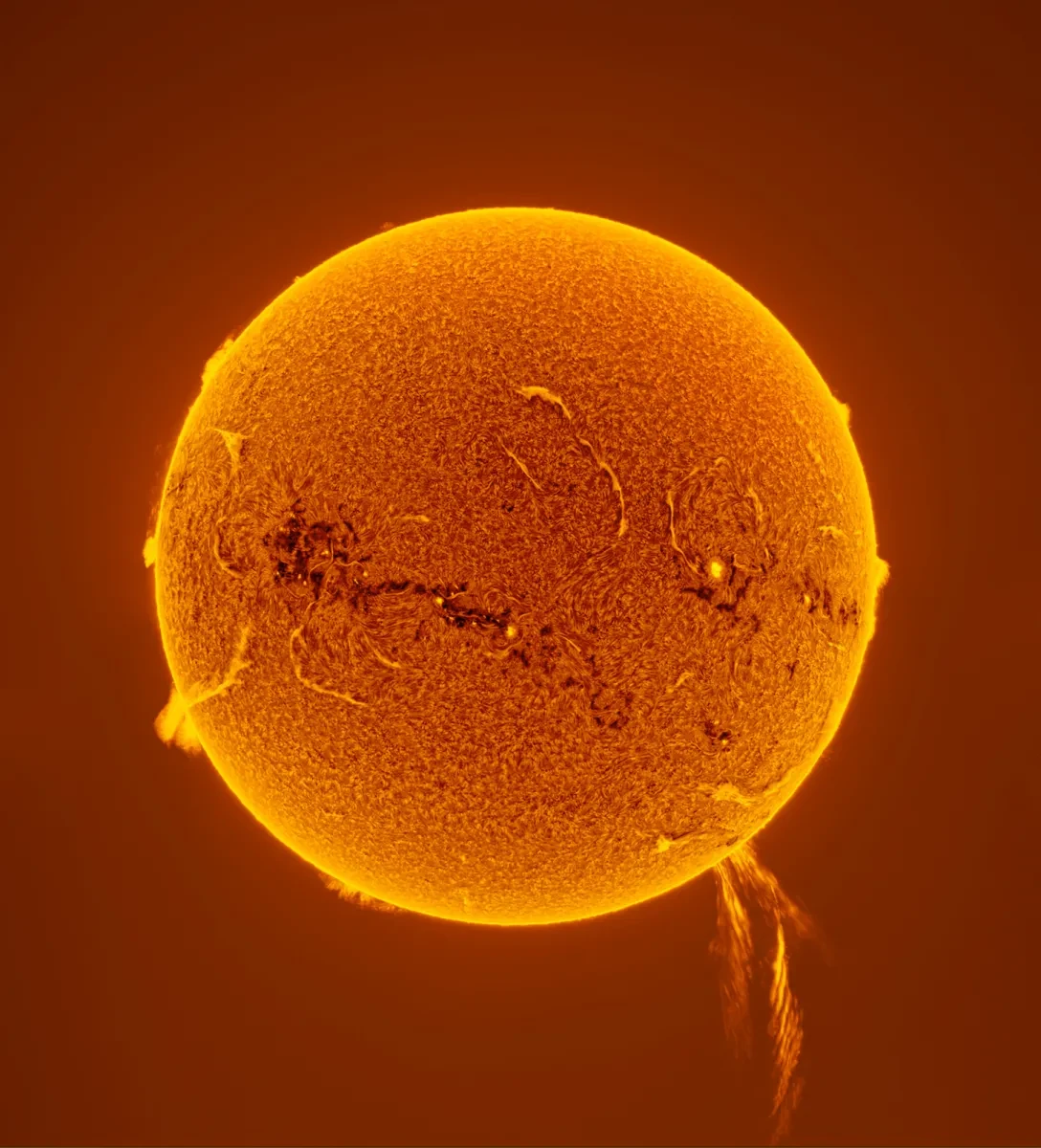 A photograph capturing a solar prominence on the bottom right of the Sun.