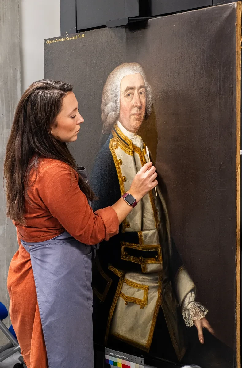 A conservator cleans the surface of an old oil painting