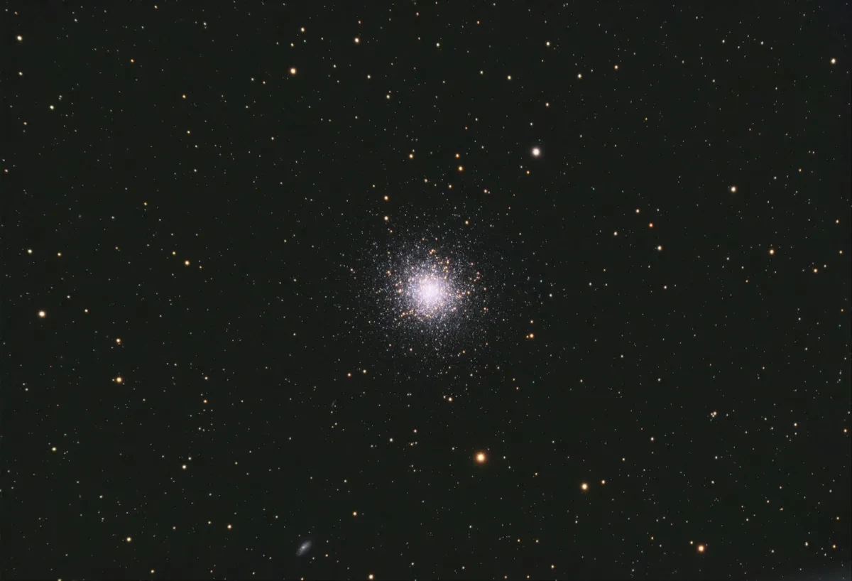 Image of bright cluster of hundreds of stars in the distance amongst a black starry sky