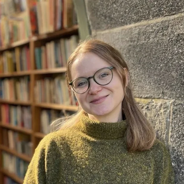 Profile photo of Caird Fellow researcher Dr Manon C Williams. She wears black-rimmed glasses and has mid-length light brown hair