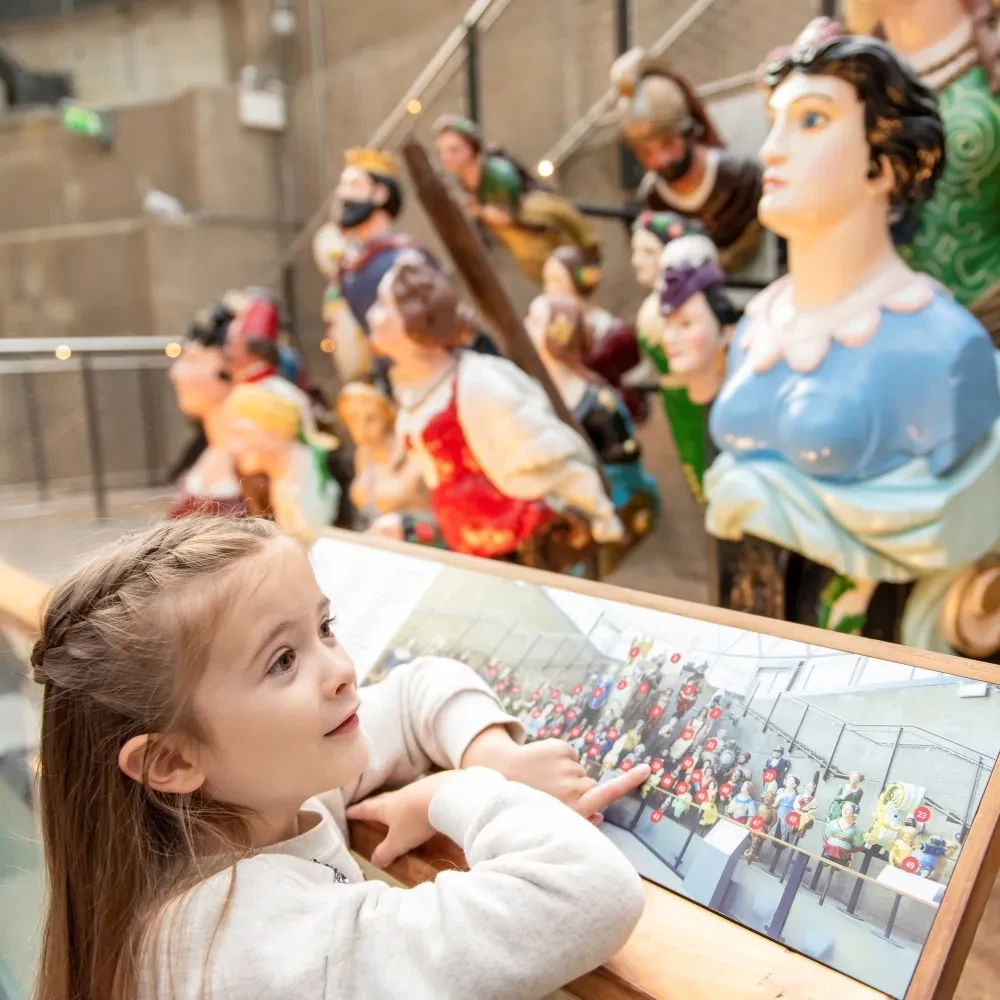 A young girl looks at a display of ship figureheads.