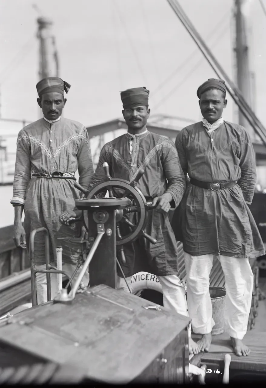Black and white photograph of three men on the deck of a boat