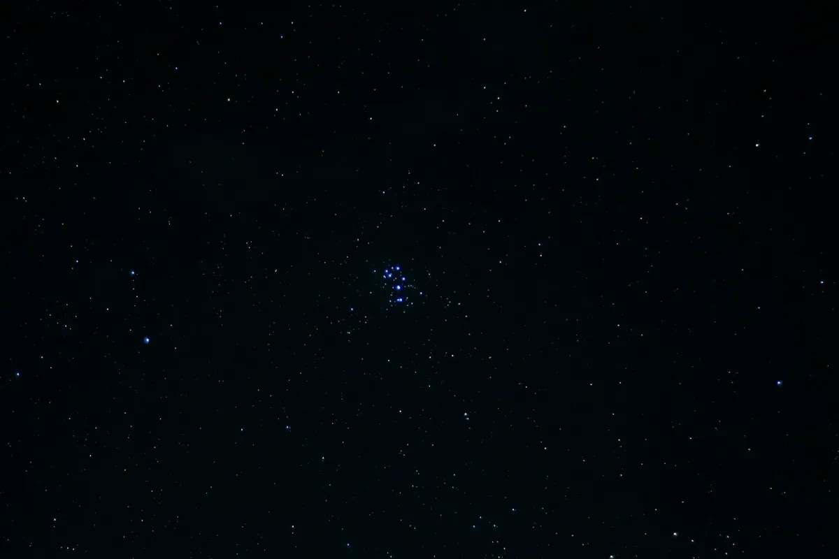 Image of dark black sky with bright cluster of blue stars in the middle