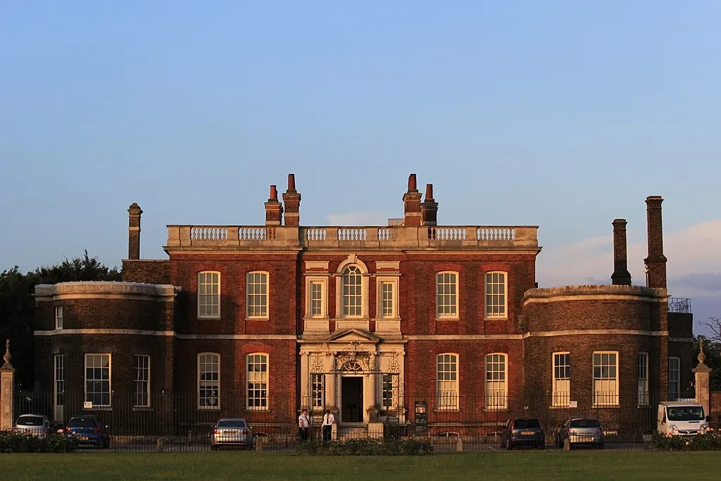 The Ranger's House in Greenwich Park at sunset, with the historic house's red brick and white framed windows lit up in the evening sun