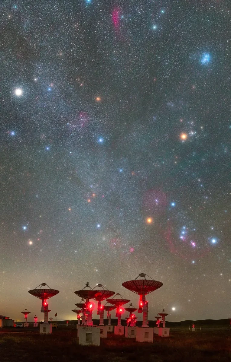 A starry sky above a collection of satellite dishes.