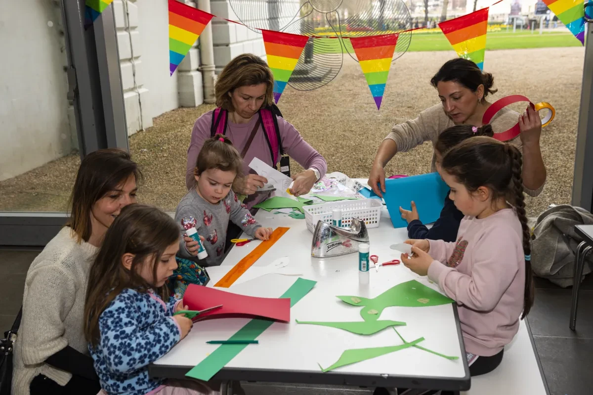 Children doing craft activity at Out at Sea festival with rainbow flags in background