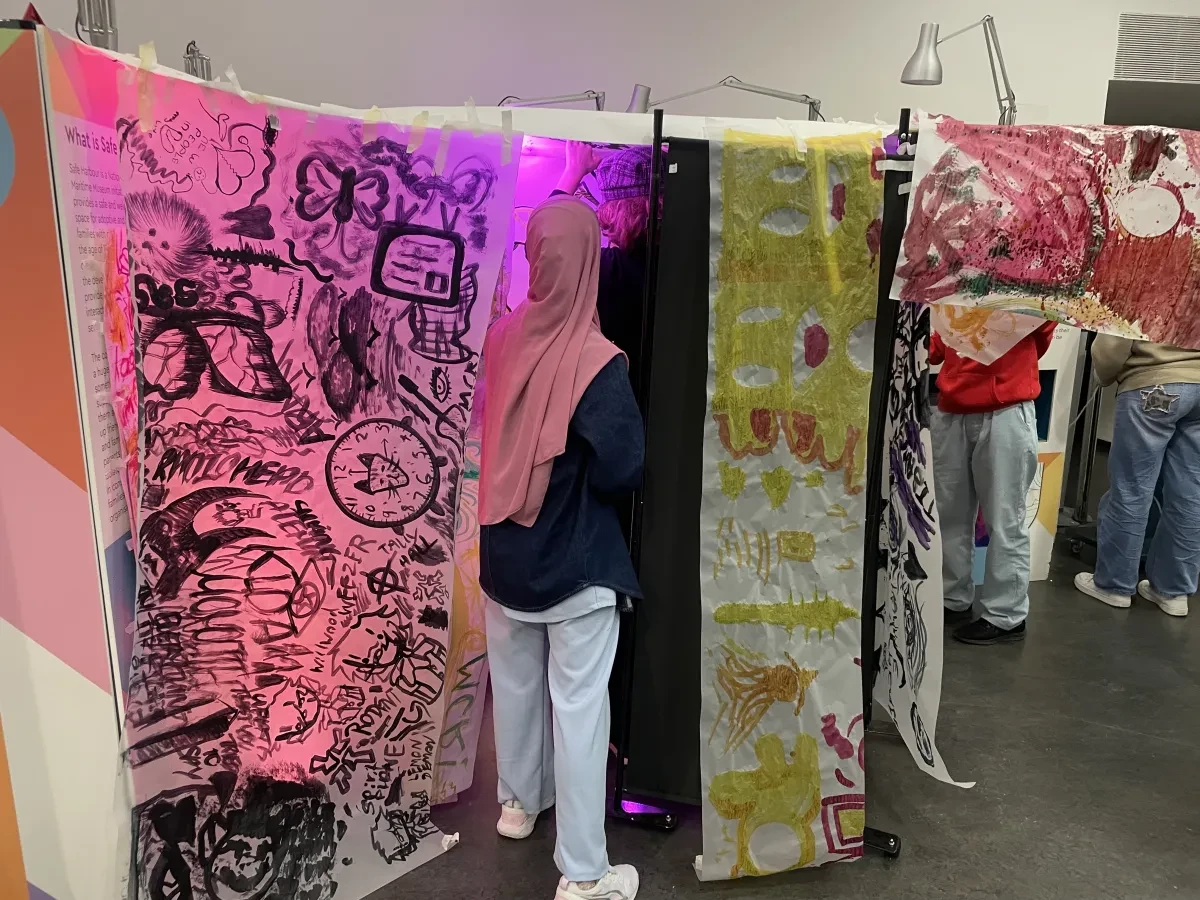 Young people attach brightly coloured pieces of painted fabric to a suspended washing line