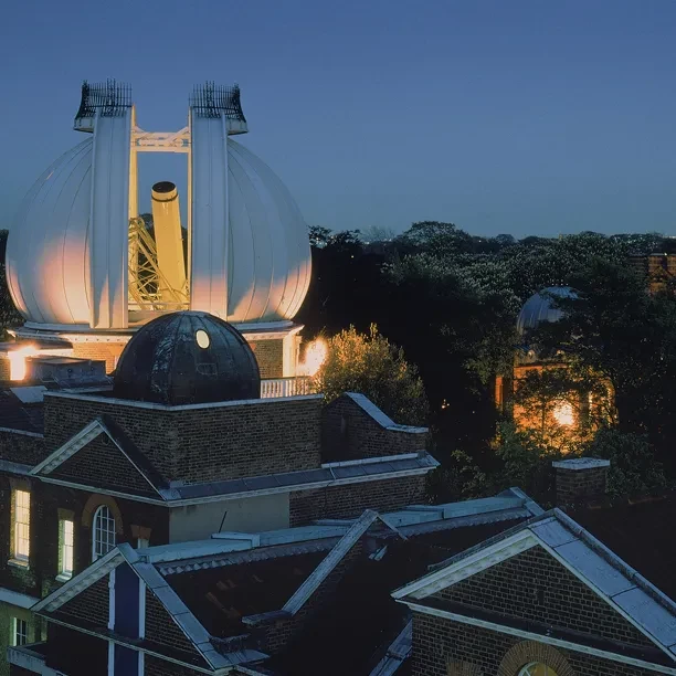 Nighttime view of a partially open dome revealing a large telescope.